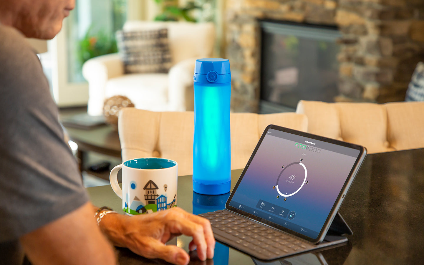 royal blue hidrate spark 3 bluetooth smart water bottler glowing green on kitchen counter next to an iPad.