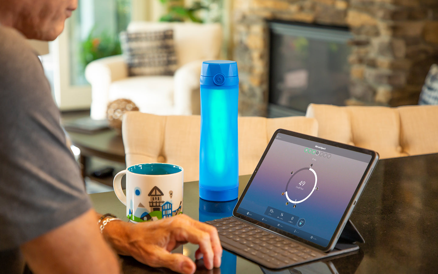 royal blue hidrate spark 3 bluetooth smart water bottler glowing green on kitchen counter next to an iPad. 