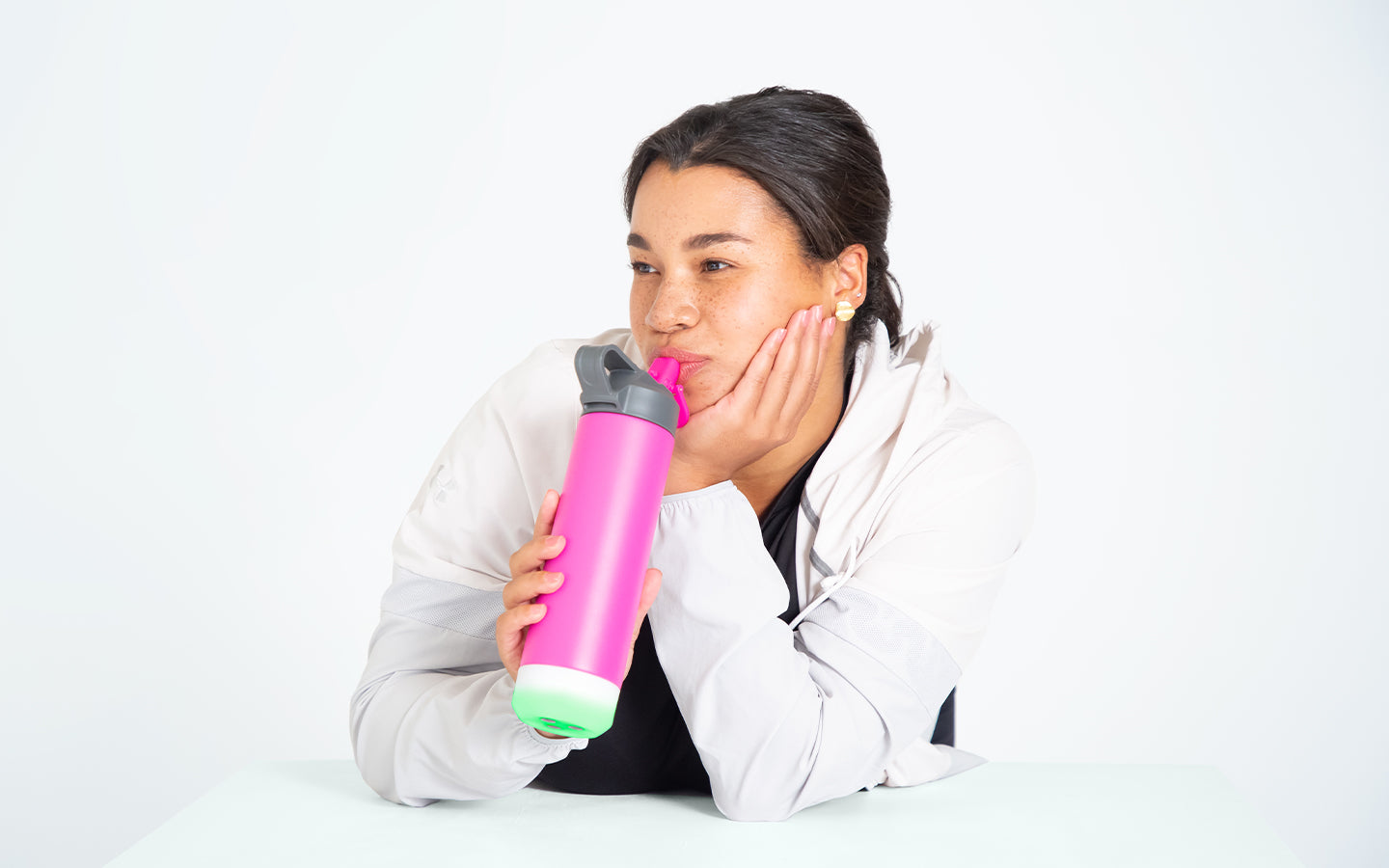 berry colored hidratespark 3 bluetooth smart water bottle next to person working-out with a kettle bell.
