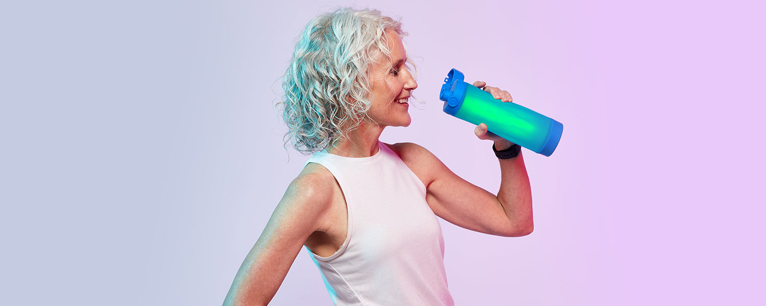 person drinking from a royal blue hidrate spark 3 bluetooth smart water bottle that is glowing.
